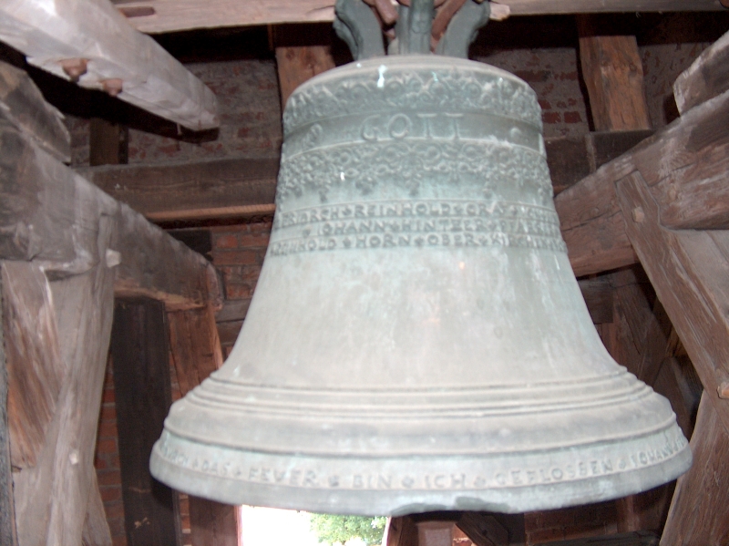 Dzwon na wieży dzwonniczej. W górnrj i dolnej cząści widoczne napisy.